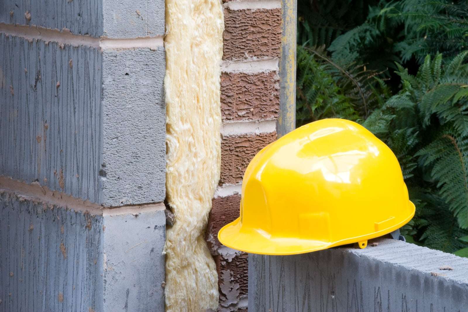 Hulmur af tegl og beton med isolering i hulrummet og en gul sikkerhedshjelm
