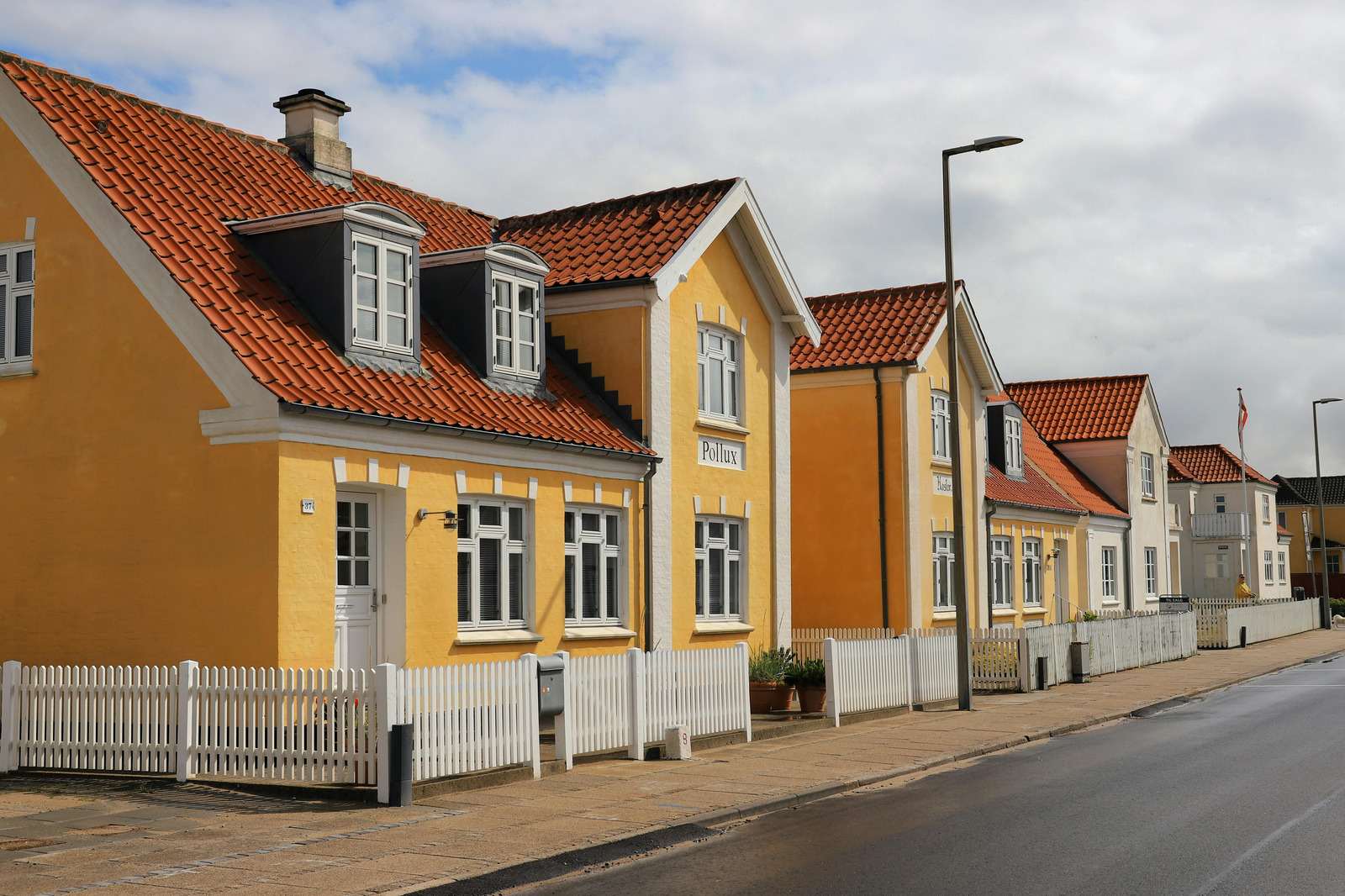 Række af gule og hvide huse med tegltage langs en gade
